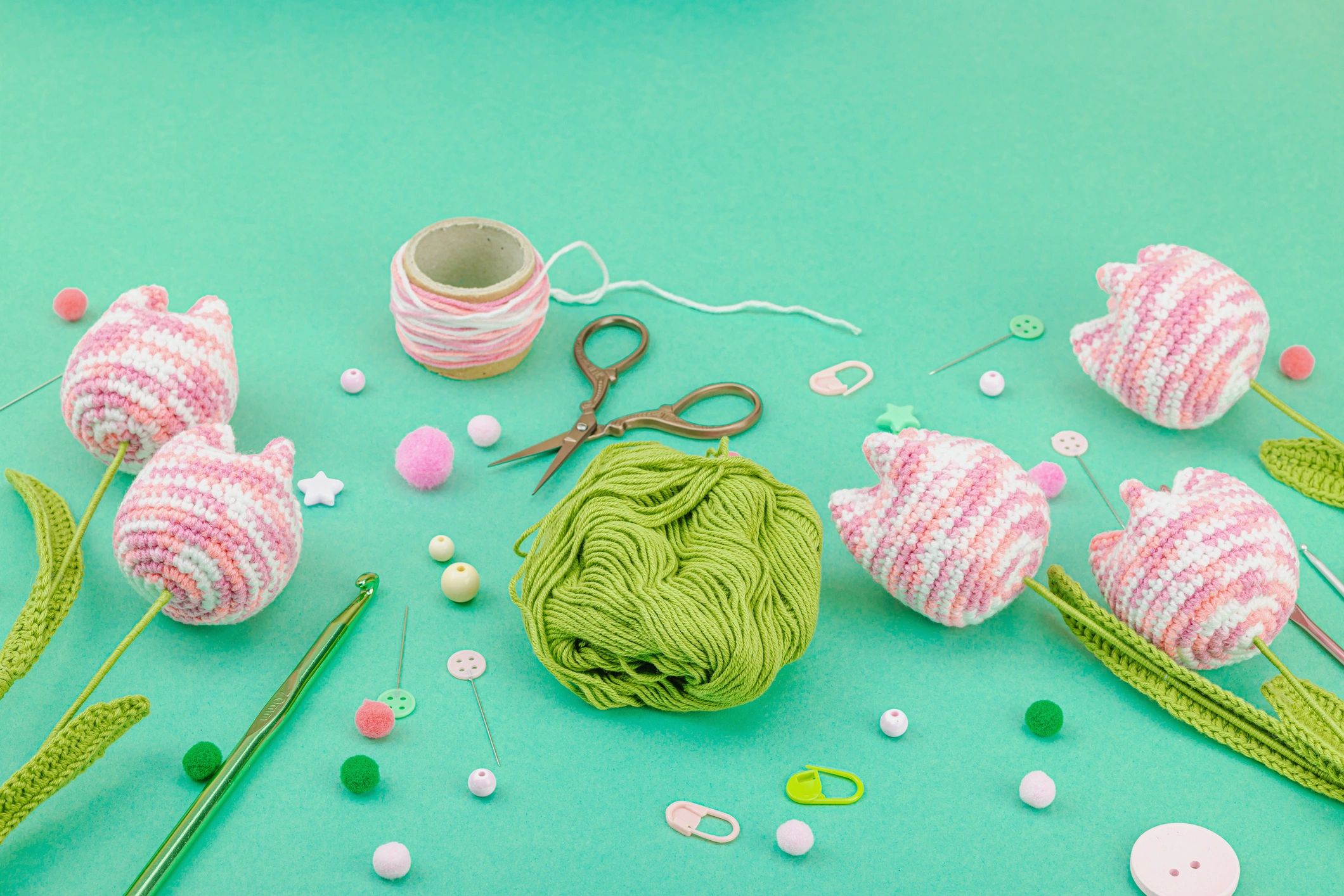Handmade crochet pink tulips arranged with knitting tools